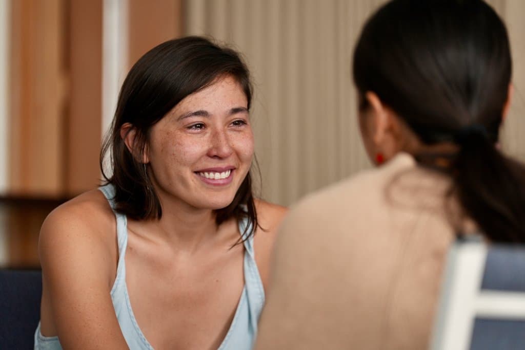 A camper smiling in close conversation with another