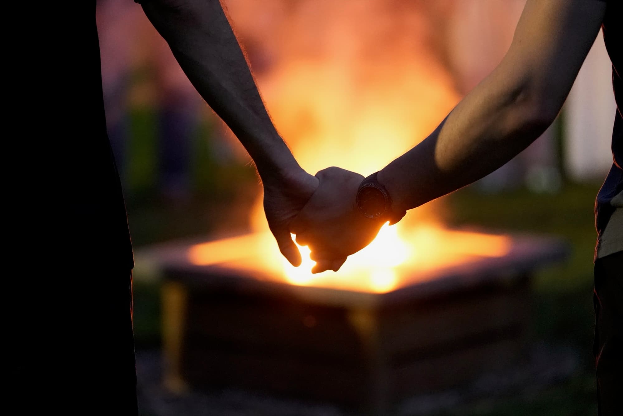 Two people holding hands by the fire at dusk