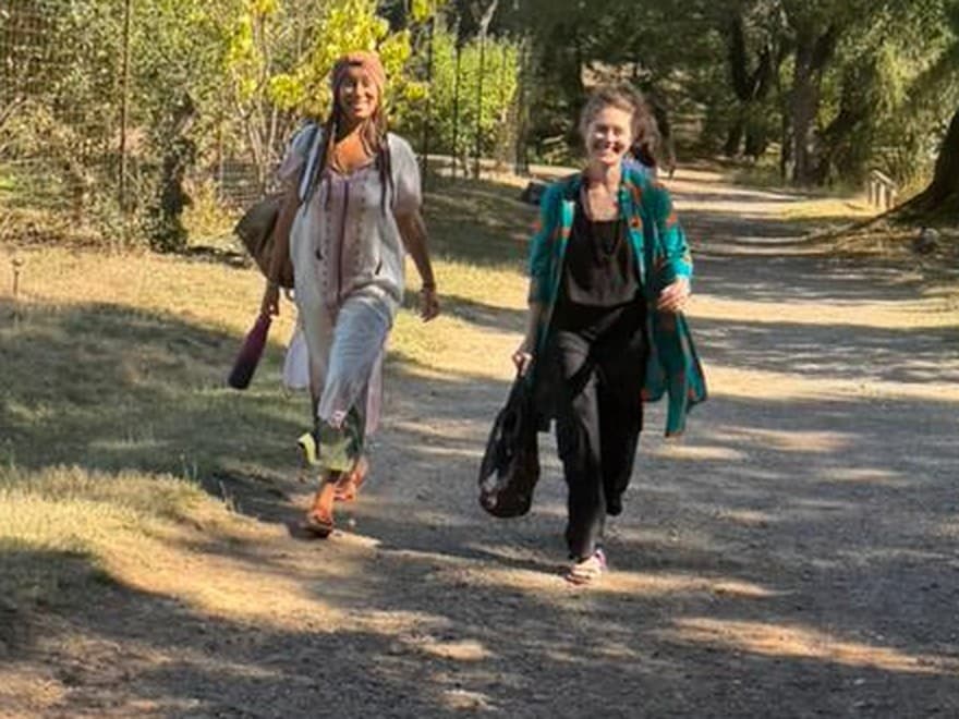 Two facilitators walking a sunlit path through the land together